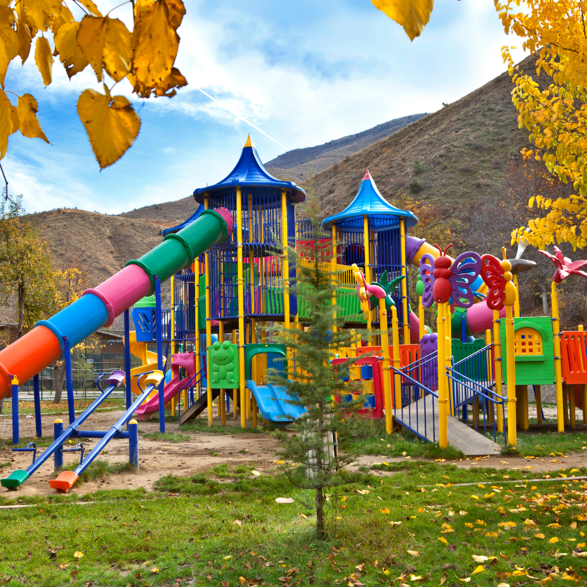 A colourful children's playground surrounded by autumn leaves